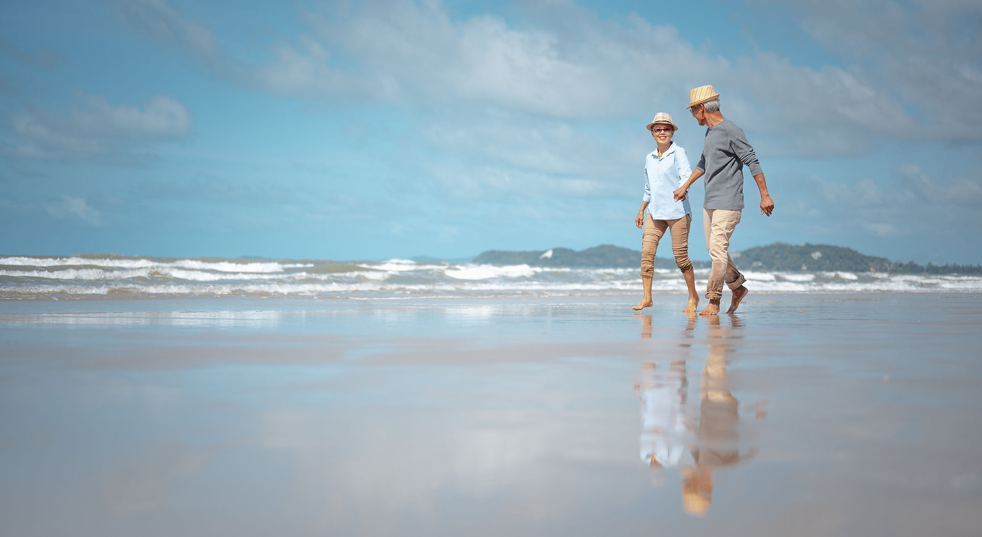 Retired Asian Couple walking on the beach